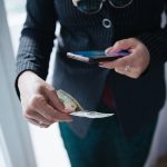 A hand holds a smartphone displaying a crypto wallet app with account balances.
