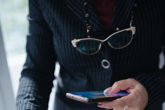A hand holds a smartphone displaying a crypto wallet app with account balances.